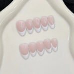 Handmade French tip press-on nails in almond shape with soft pink base and white tips